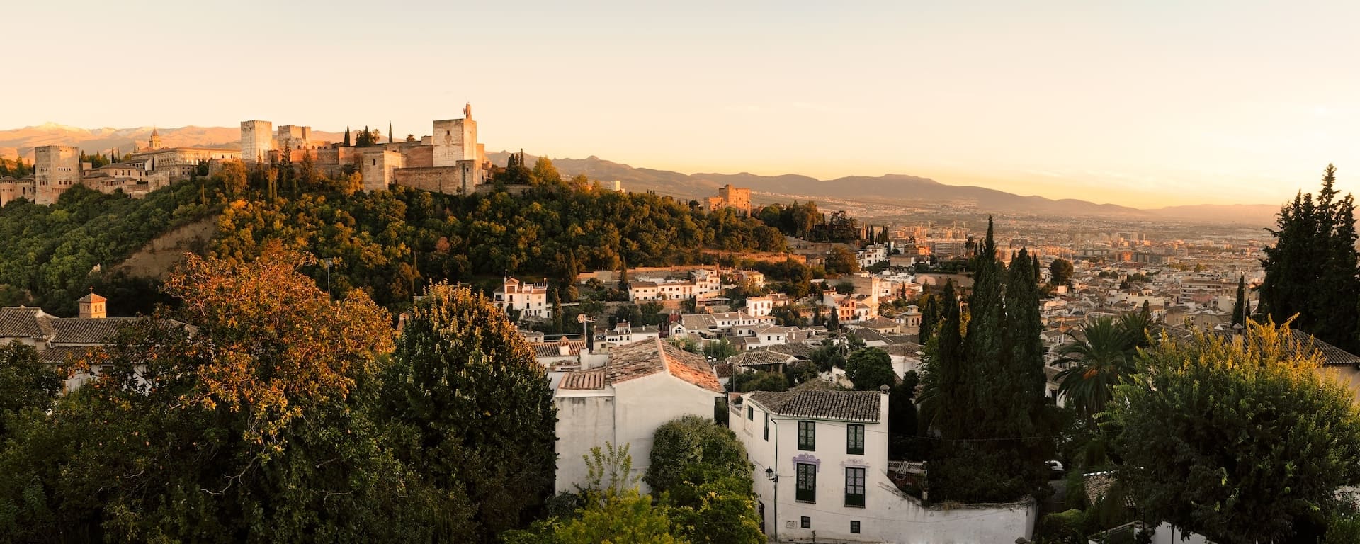 Sunset view of the Alhambra in Granada Spain overlooking historic city and surrounding mountains.