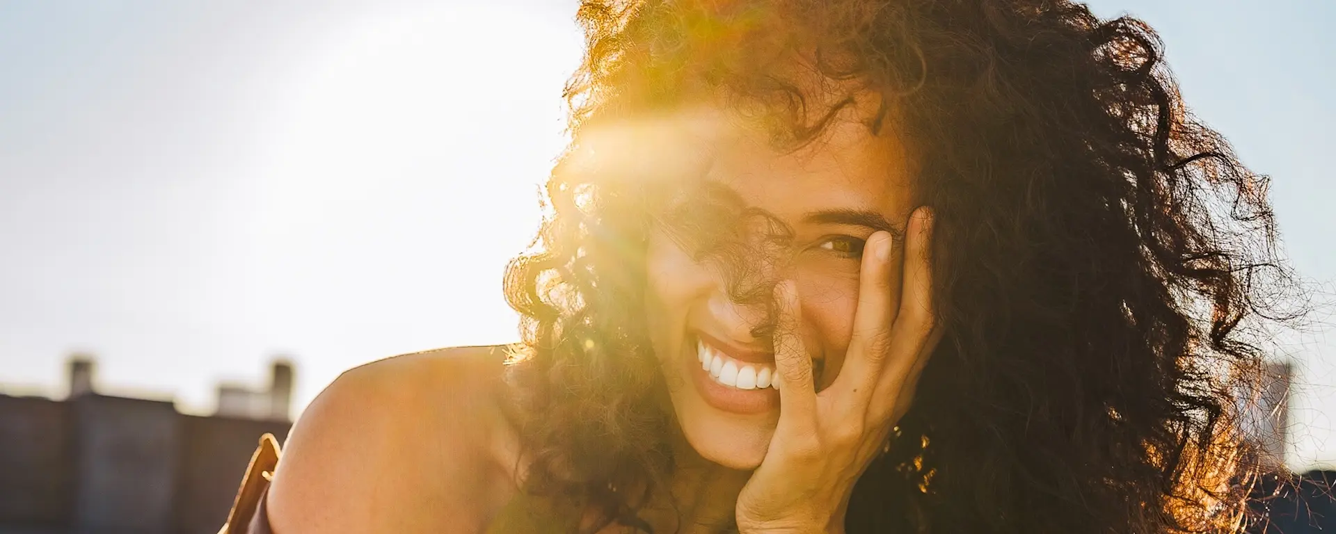 Alexandra Metz The Pitt actress smiling in warm sunlight with natural curls, golden light across her face
