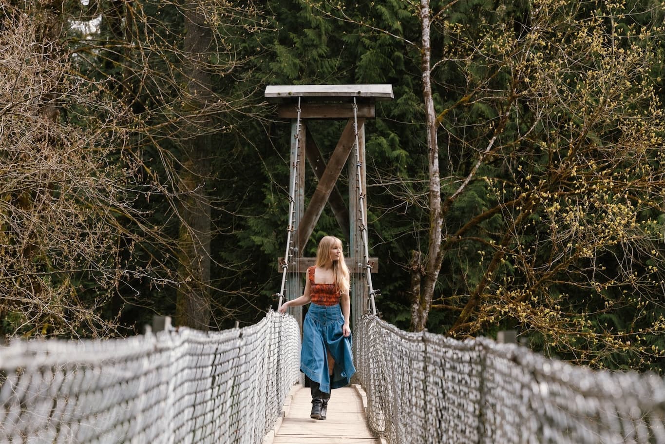 Debs Howard relaxing on a grassy hillside in a black top, white skirt, and boots, photographed outdoors for Ebby Magazine