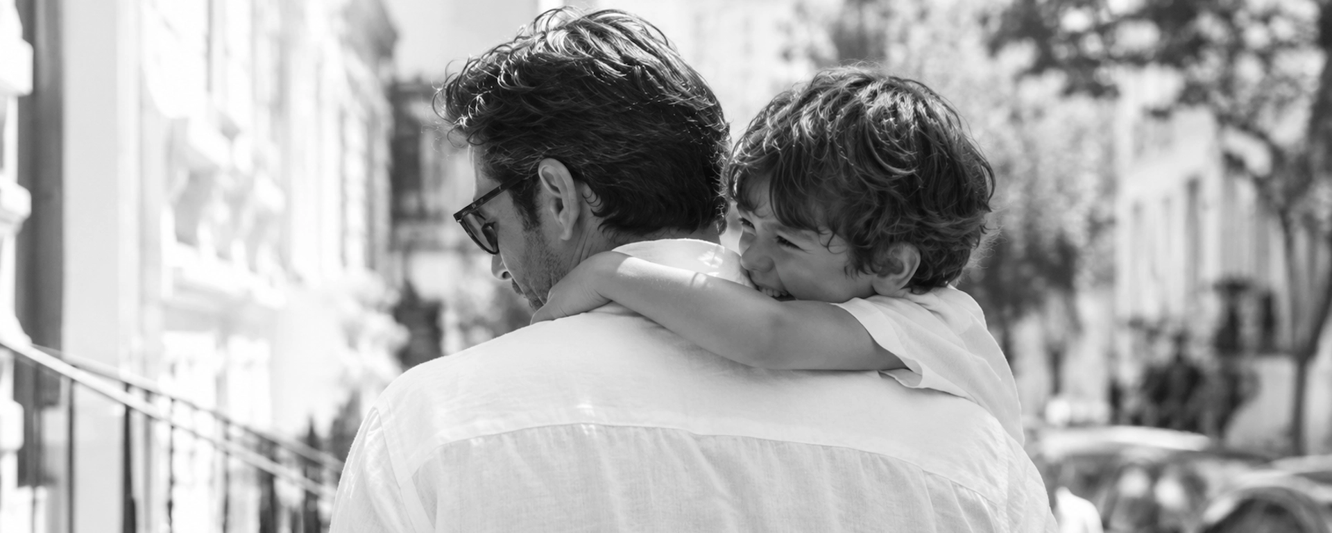 Stylish father and son sharing a joyful moment in a bright city street during summer