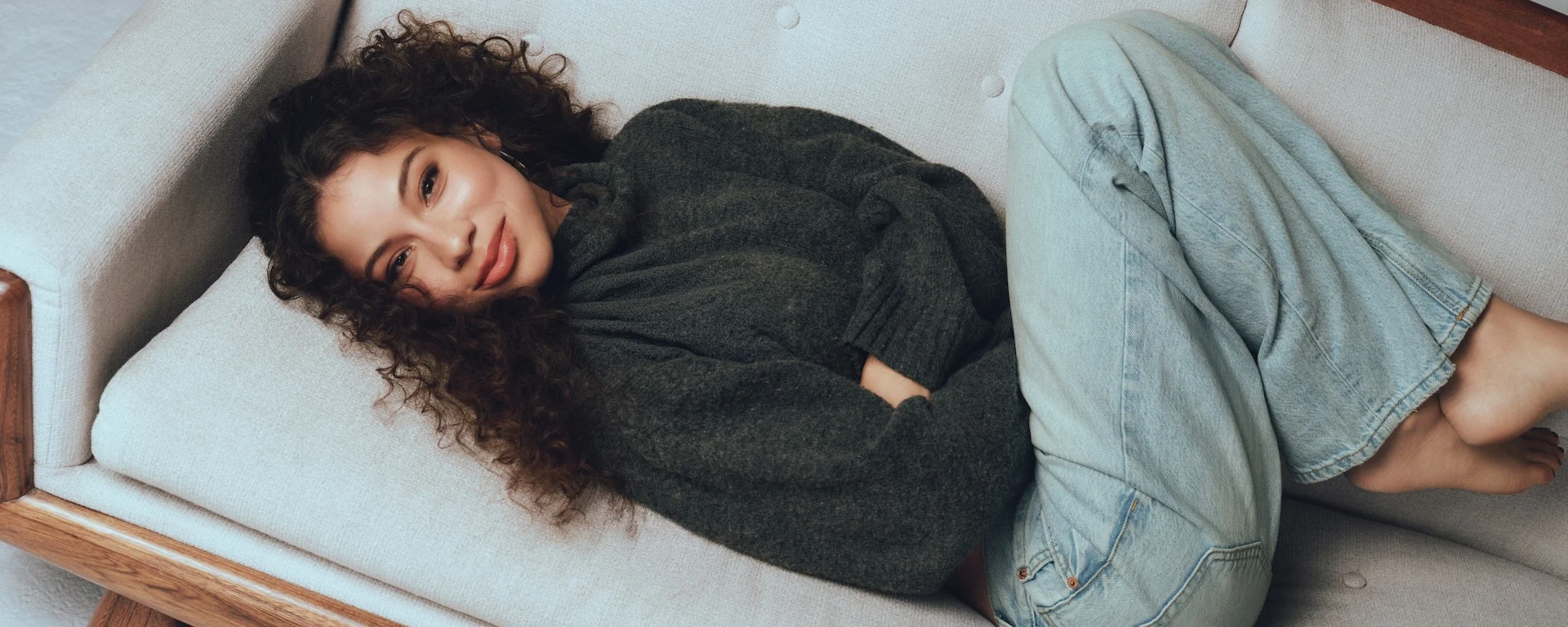 Actress Kiara Romero reclining on a couch in a portrait featured in Ebby Magazine.
